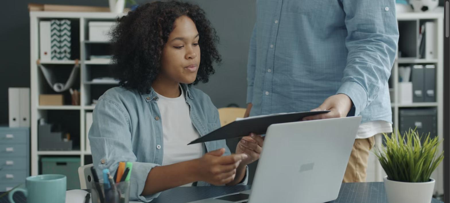 Two colleagues reviewing documents at an office desk, representing resume and cover letter review