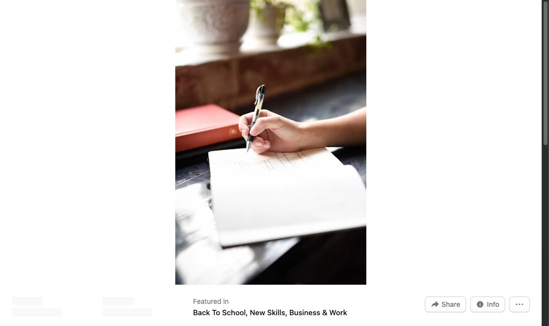 Hand holding a pen writing in a notebook on a table