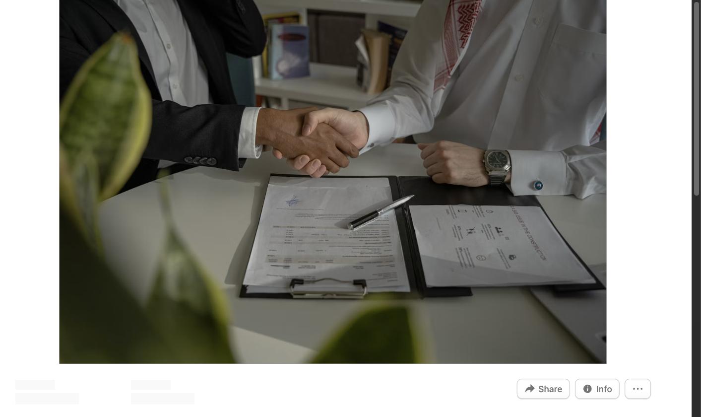 Two people shaking hands over a folder of documents, symbolizing a job referral