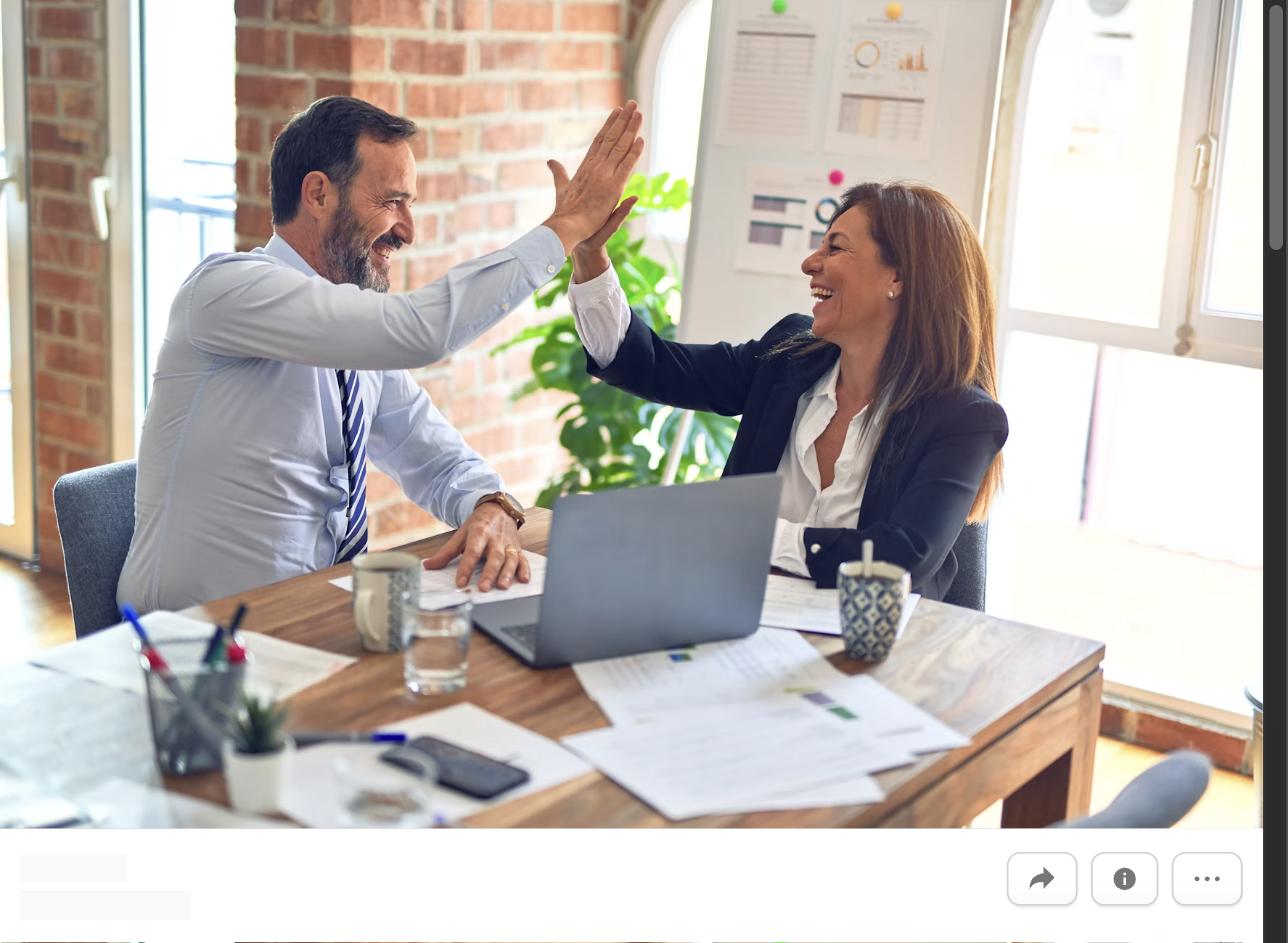 Two colleagues high-fiving over a desk, representing writing a cover letter for an internal position