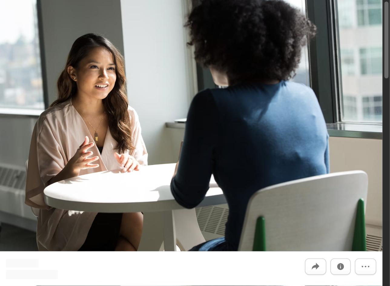 Two women having a conversation across a table, representing negotiating during the interview process before receiving an offer