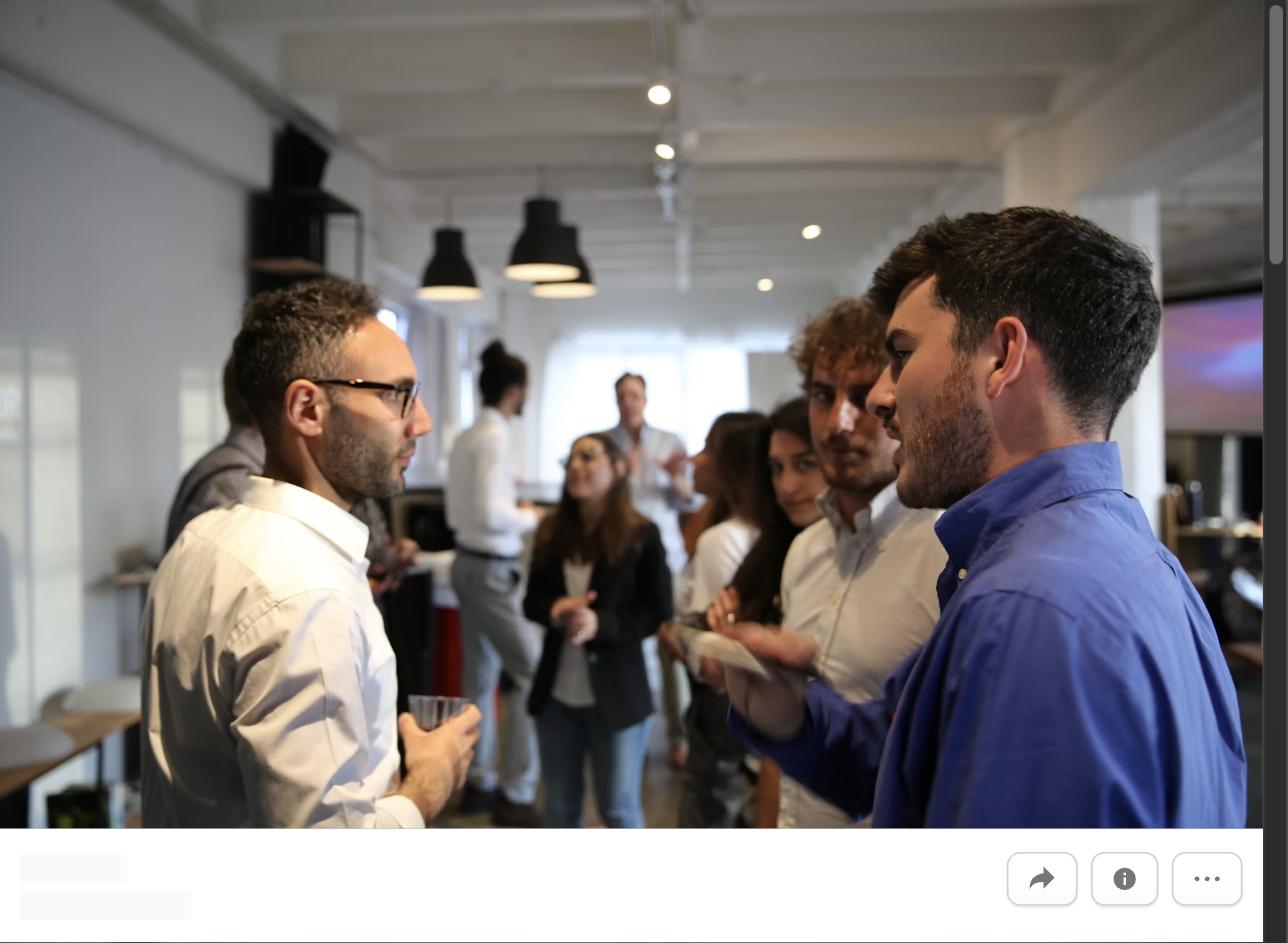 A group of professionals talking and networking at an office event, representing building a network that helps your career long term