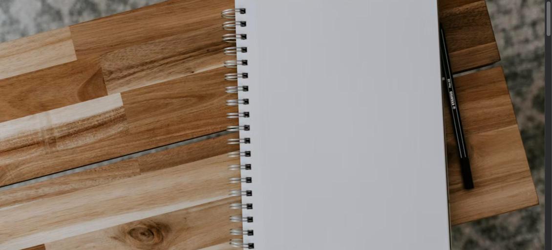 Blank spiral notebook and pen on a wooden desk, symbolizing white space on a resume