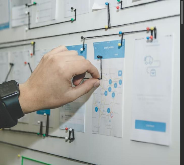 Hand pinning notes on a planning board to map out a strategy