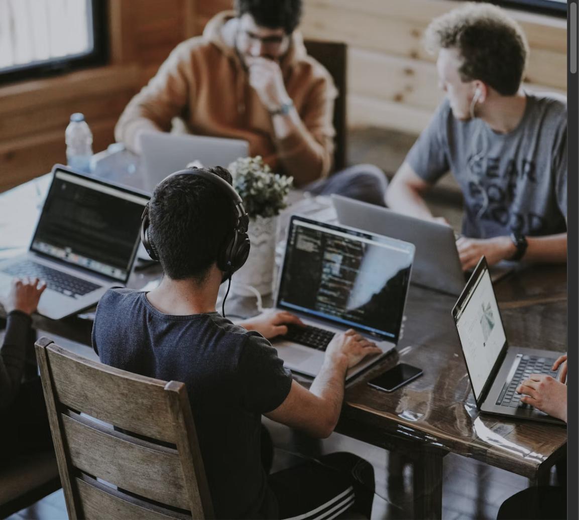 Casual startup team working together on laptops around a table