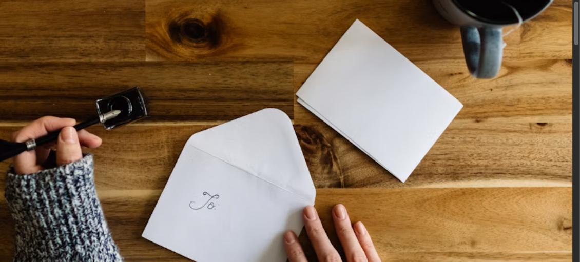 Hand writing a letter with a pen on a wooden desk, representing a cover letter for a promotion