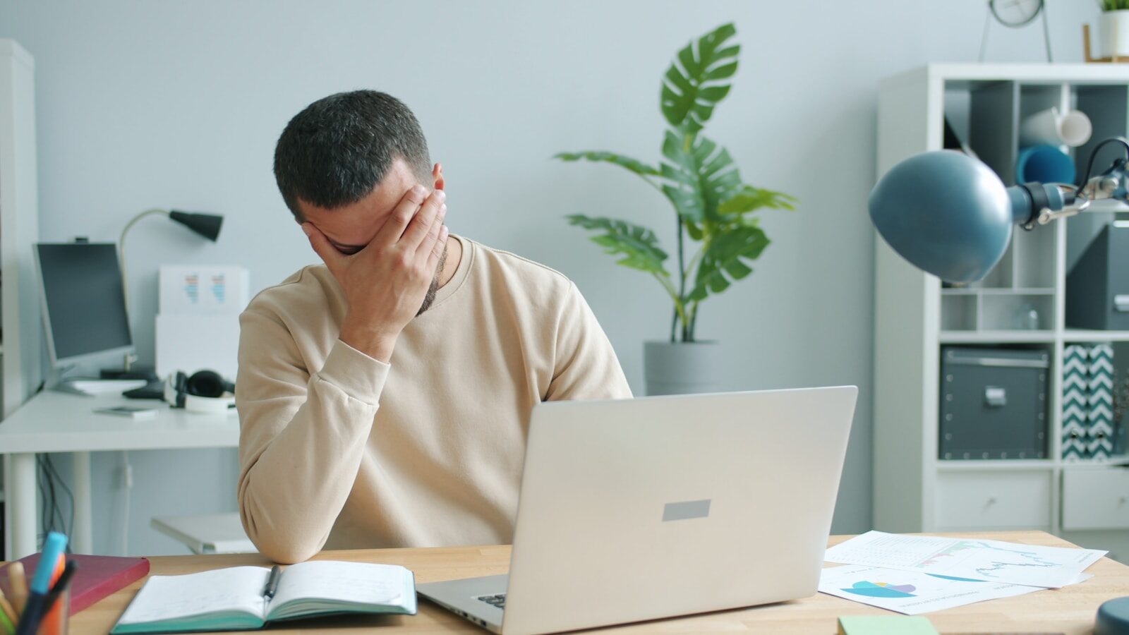 Stressed employee holding his head while working at a desk in a toxic workplace