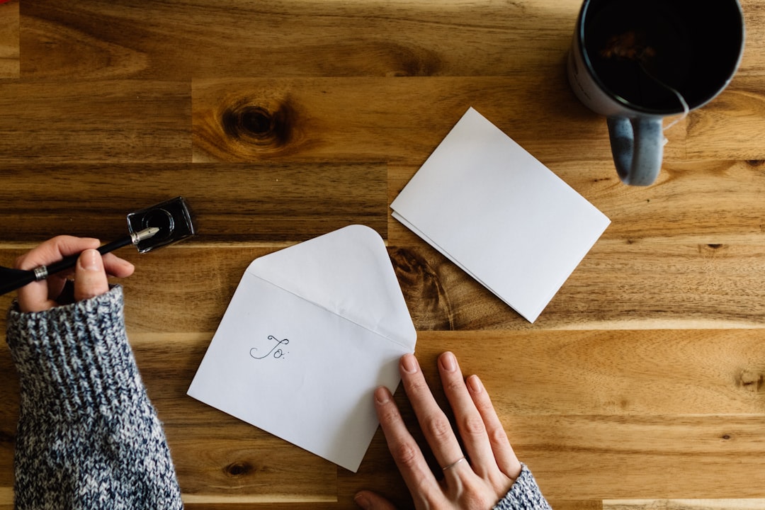 Person writing a cover letter at a desk next to a cup of coffee