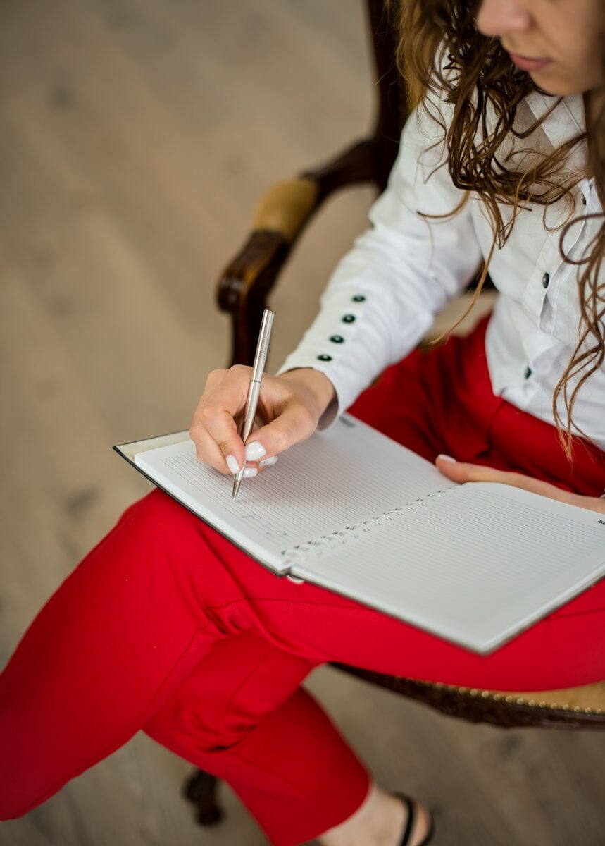 Woman writing and revising notes in a notebook, representing using AI tools to improve a resume
