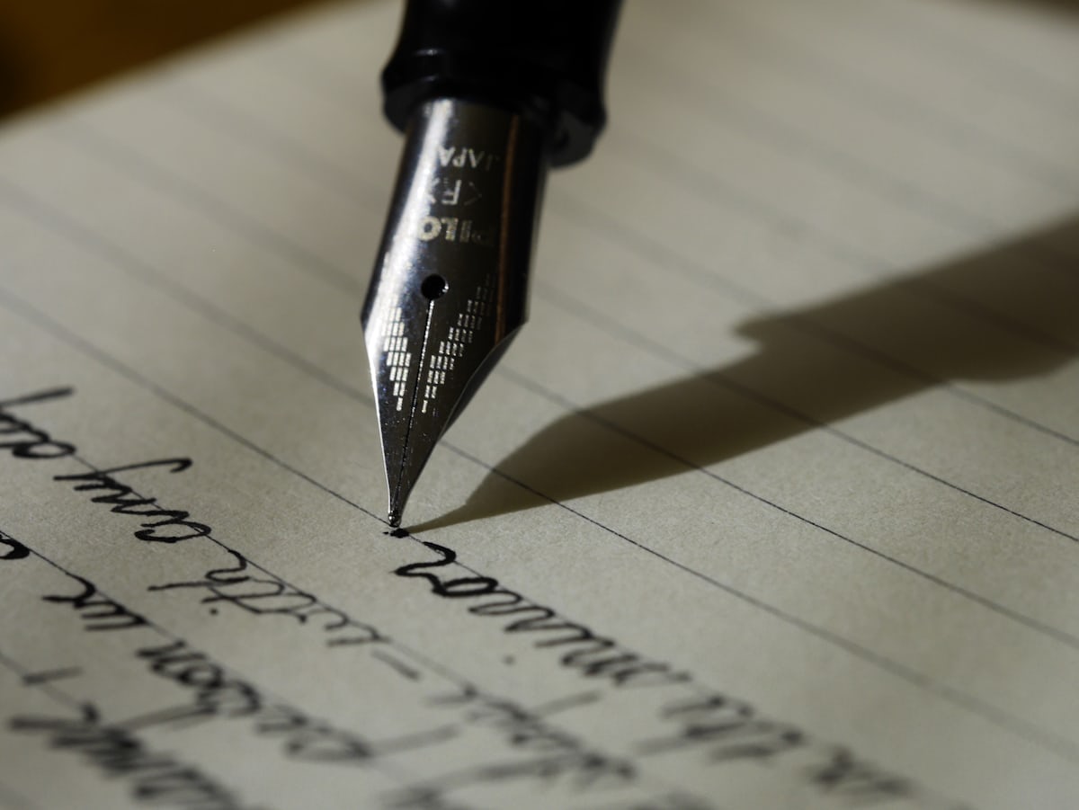 Person writing a cover letter by hand at a desk