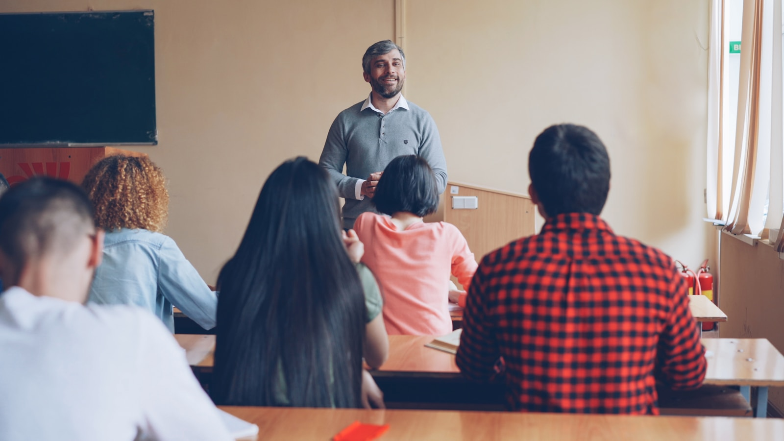 Teach English abroad: a smiling teacher addressing a diverse group of adult students in a classroom, representing the kind of language classroom English teachers work in overseas