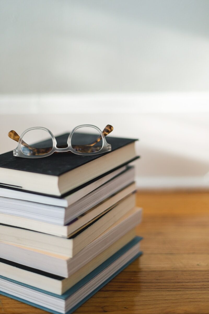 Reading glasses resting on a stack of books on resume writing