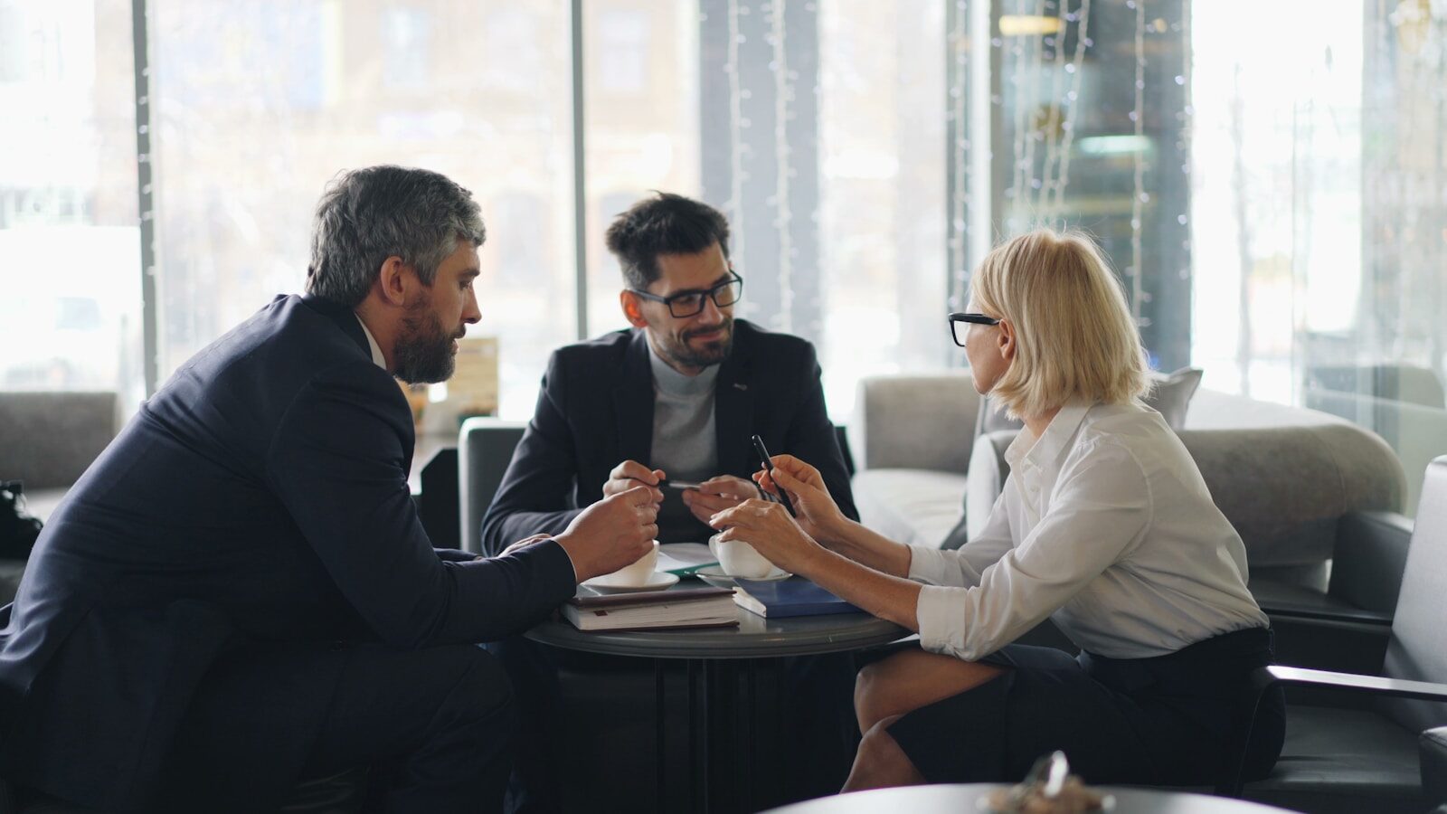 Become a consultant: a consultant in a business meeting discussing strategy with two clients in a modern office