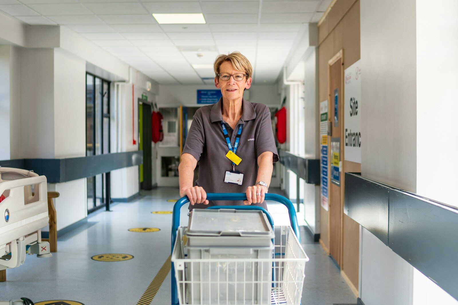 Become a nurse: a healthcare worker with an ID badge walking a hospital corridor, illustrating where the RN shortage is most acute outside major metro areas