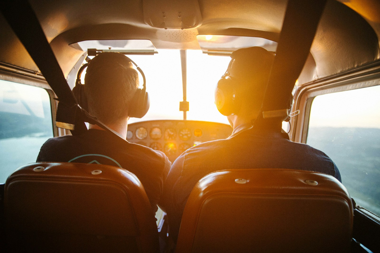 Become a pilot: the view from inside a small training aircraft with two seats backlit by the sun, representing the flight hours student pilots log before earning a certificate