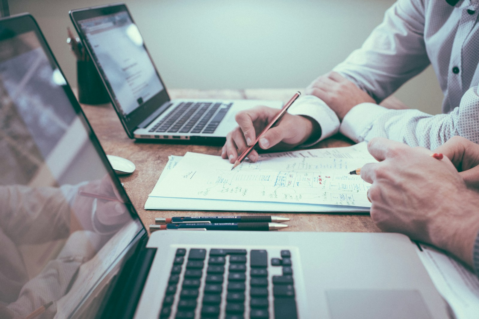 A real estate agent reviewing paperwork and a laptop in an office, weighing the role and uses of real estate virtual assistant support