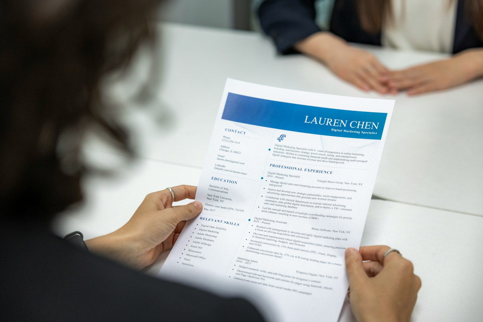 A hiring manager reviewing a printed application document at a desk