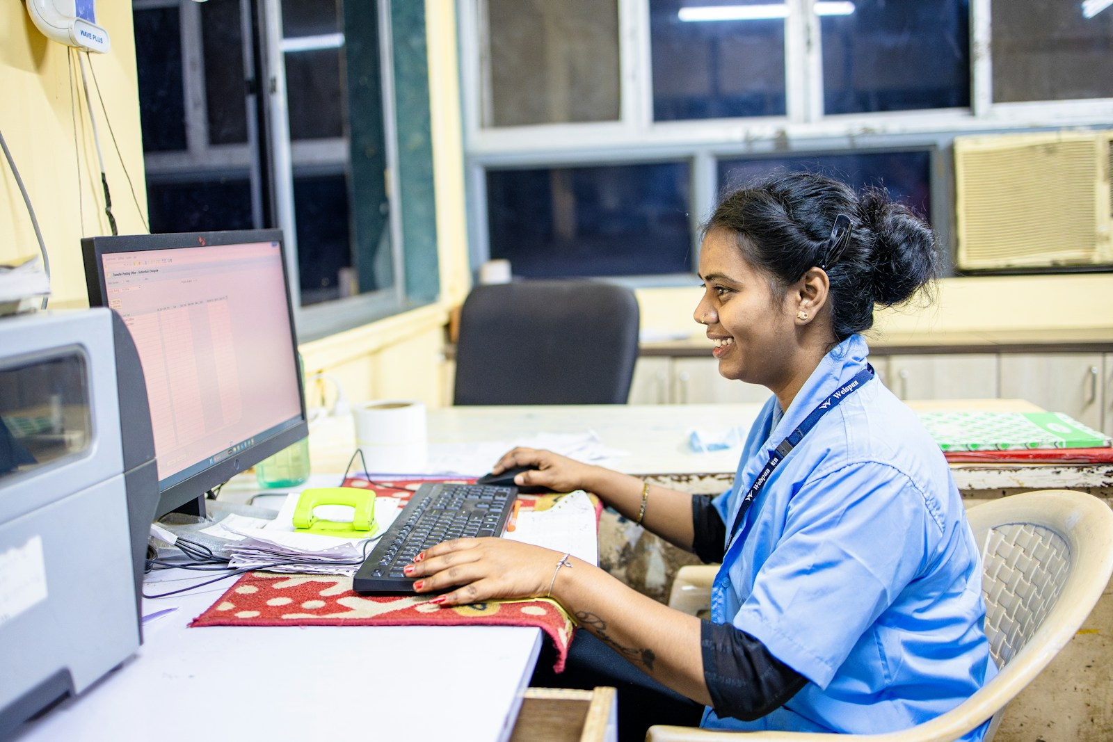 A medical transcriptionist typing at a computer with medical documents, illustrating the medical transcriptionist boom claim