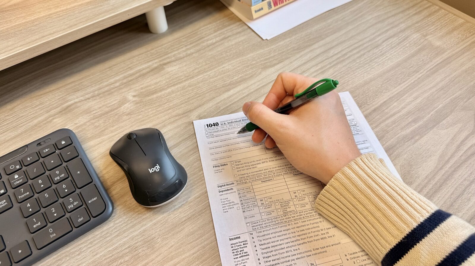 A hand filling out paperwork at a desk, representing the employment dates that get checked when lying on your resume is suspected