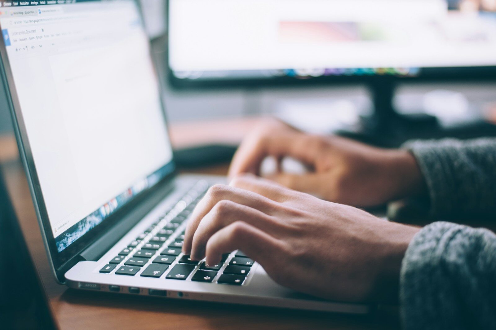 Hands typing on a laptop keyboard with a notebook nearby, representing the portfolio work involved in starting a career in IT