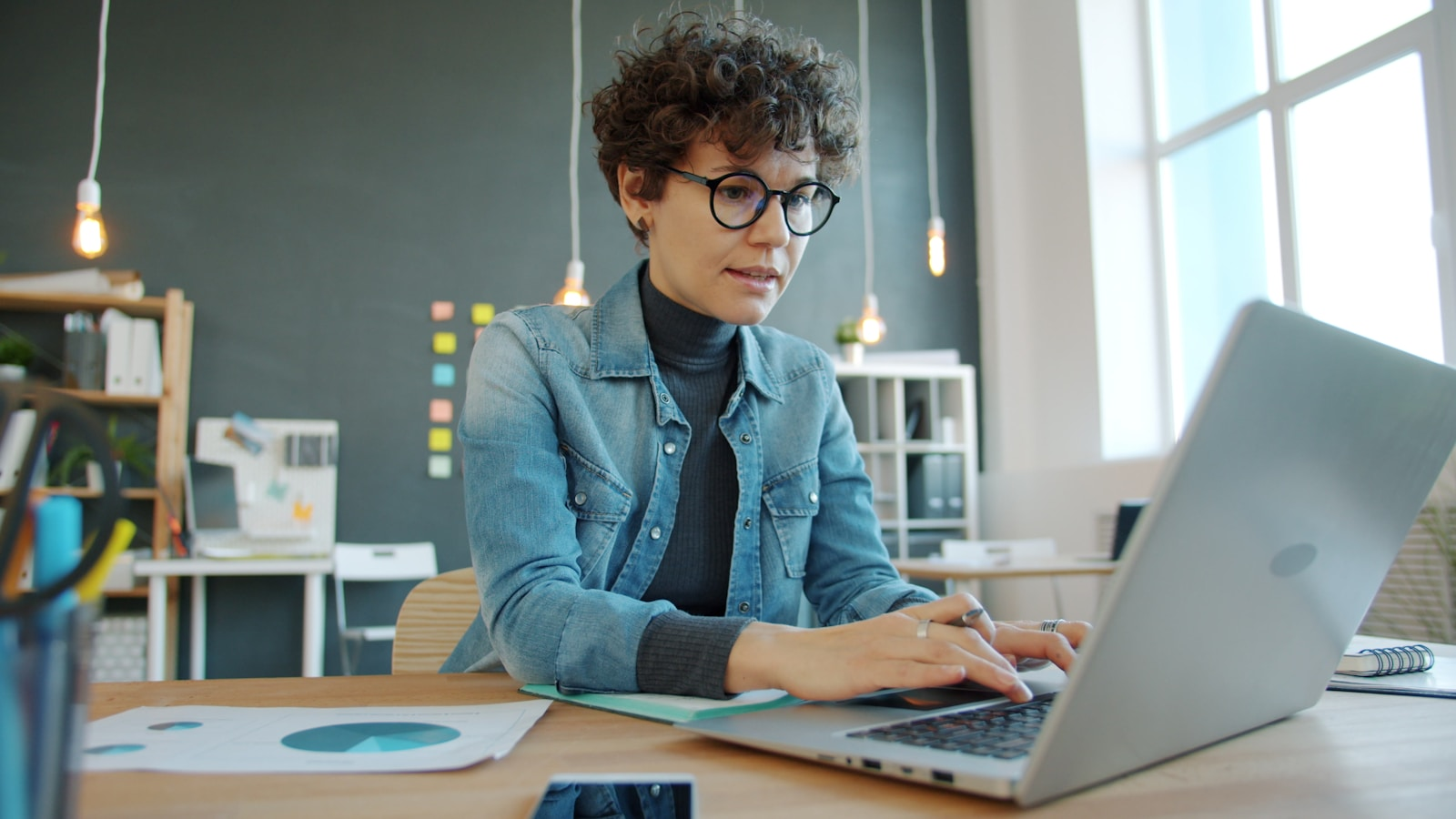 A professional working on a laptop in a modern office, representing a changing workplace
