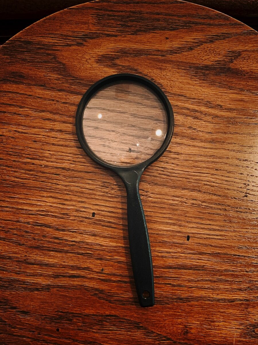 A magnifying glass held over a printed document, representing the fact checking that catches lying on your resume